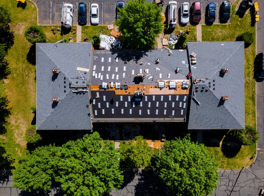 A Farmington roofing contractor nailing shingles with air gun, replacing roof cover protection being applied, apartment development
