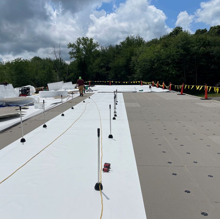Roofer installing TPO membrane on a commercial roof